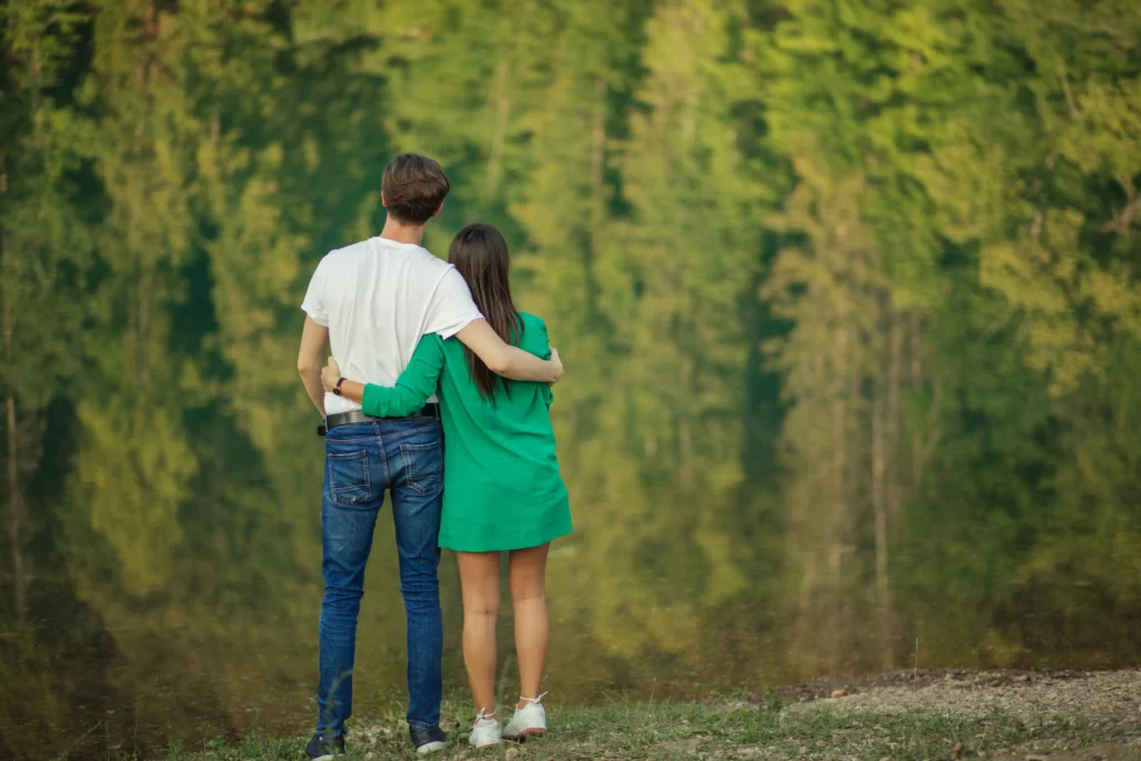 young couple embrace near calm lake utc